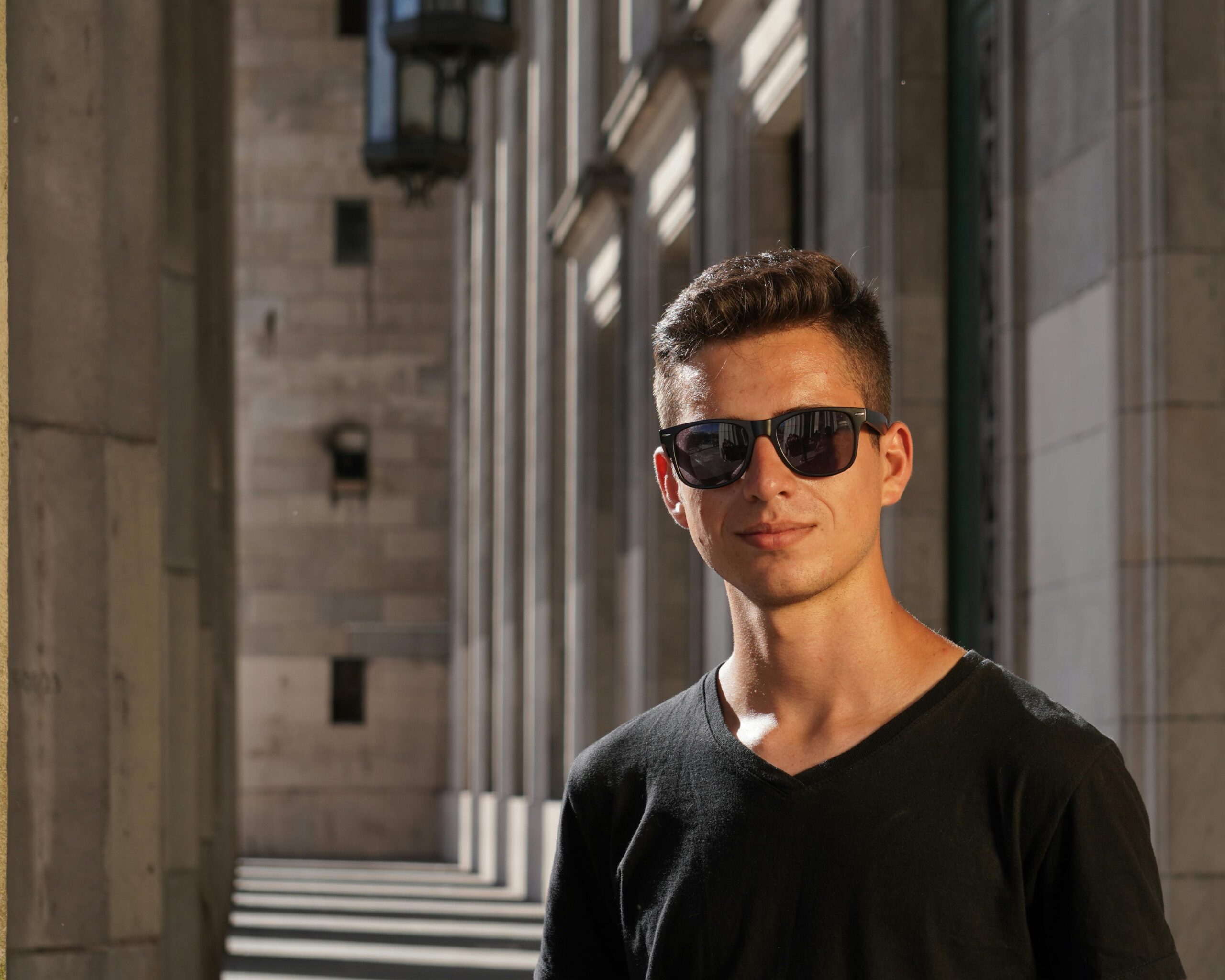 Confident young man wearing sunglasses during summer in Buenos Aires architectural setting.